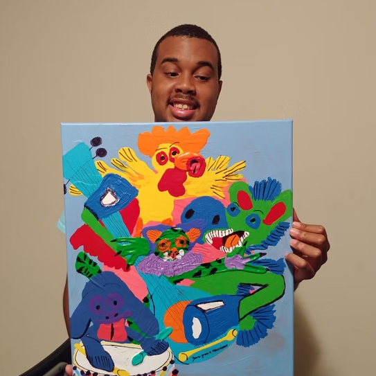 Dyshaunn smiles while posing for his picture and looking away from the camera. In his hands he is holding a painting of brightly color abstract animals playing music.