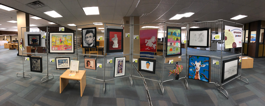 metal racks containing multiple artworks stand in library setting