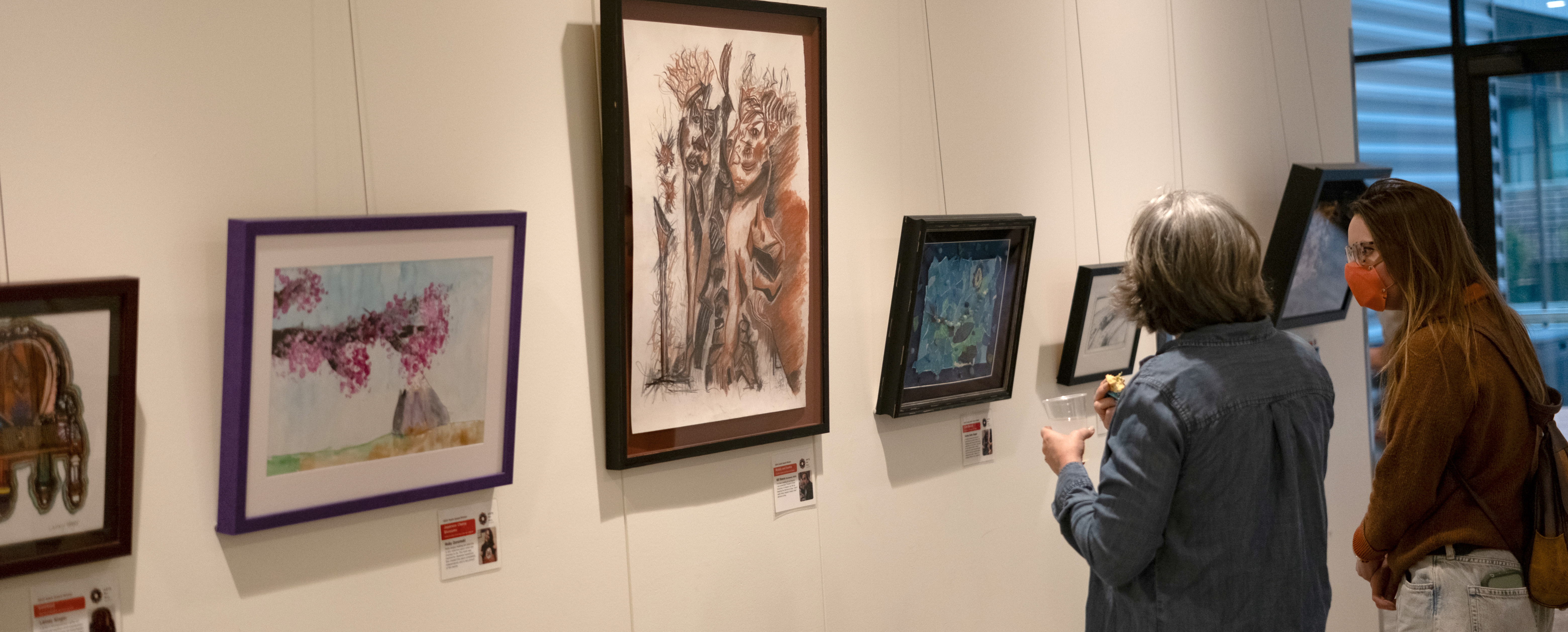 Two people facing away from the camera enjoy viewing the Creative Power collection on display at the Creative Power Awards Celebration 2025.